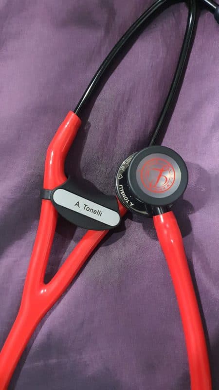 Littmann stethoscope with red tubing and an engraved name tag clipped to the tubing